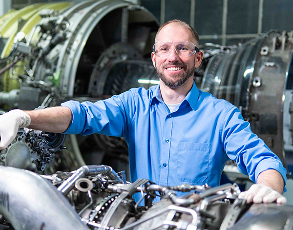 Poland employee standing with engine.