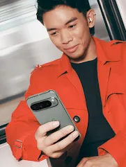 A person in a bright red jacket looks at their Pixel phone while wearing Pixel Buds.