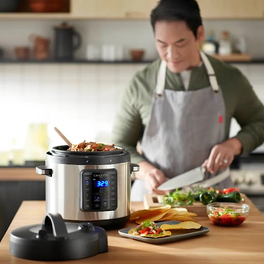 Ein Koch mit Schürze kocht in einer Küche. Im Vordergrund ist ein Smart Crock-Pot zu sehen.
